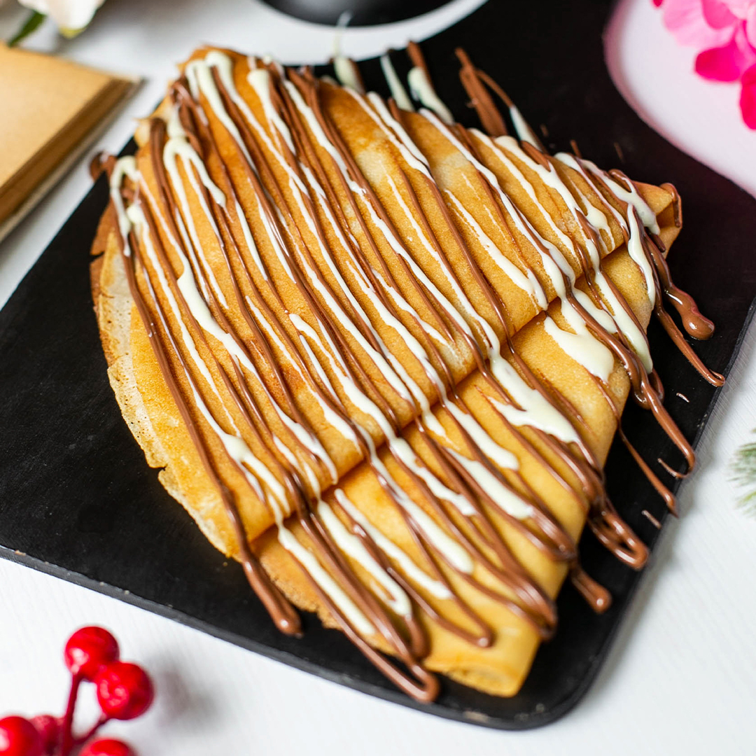 side-view-crepe-with-chocolate-cocoa-syrup-wooden-cutting-board